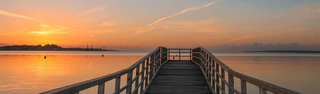 Bestattungsvorsorge in Neu-Anspach: Steg am Meer bei Sonnenuntergang als Sinnbild für Abschied, Erinnerungen und persönliche Vorsorge.