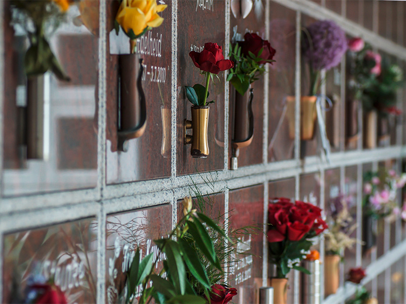 Bestattung in Urnenwand auf einem Friedhof mit verschlossenen Urnennischen als platzsparende Form der Urnenbeisetzung.