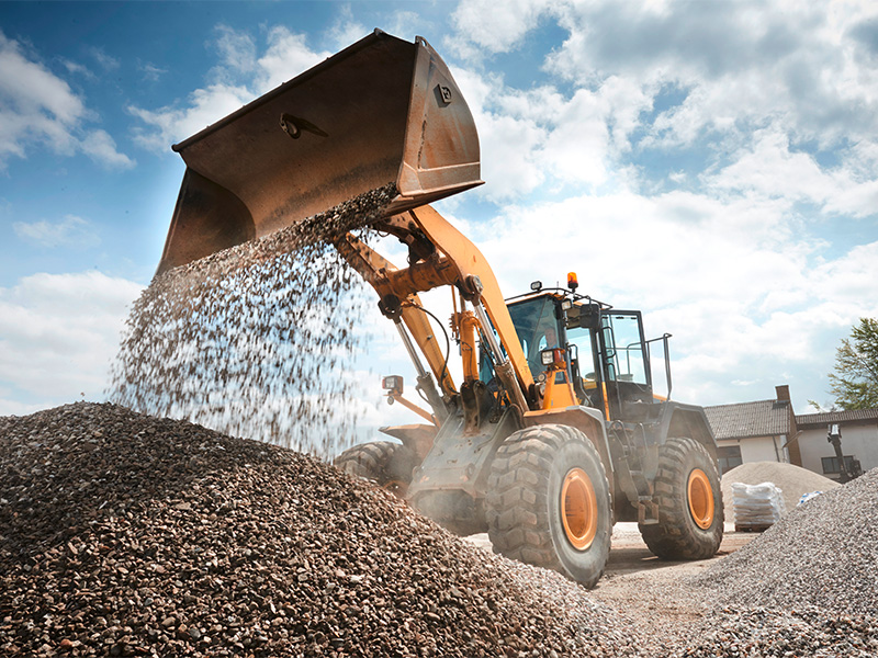 Bagger bewegt großen Haufen Estrichsand auf Baustelle für Bauarbeiten und Bodenvorbereitung im Außenbereich