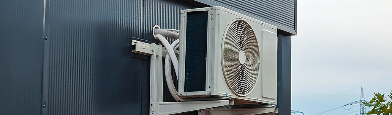 Außeneinheit einer Klimaanlage auf einem Metallgestell an der Außenwand eines Gebäudes montiert.