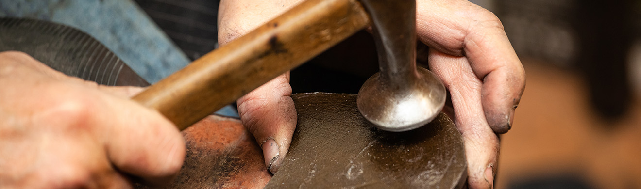 Hände eines Schuhmachers reparieren Schuhabsatz, präzise Arbeit, traditionelle Orthopädie-Schuhtechnik in Frankfurt für gesunde Füße.